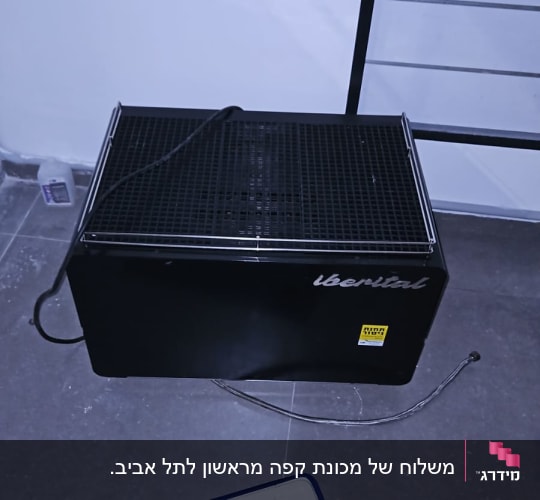 מכונת קפה שחורה עם כבל חשמל על רצפה אפורה